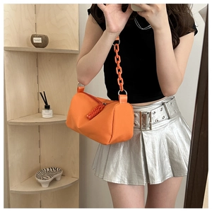 Detail of orange cylindrical crossbody bag with chunky plastic chain strap and woven zipper