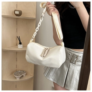 Close-up of white crossbody bag featuring woven dual zippers and metal chain strap detail