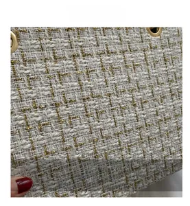 Close-up of white and gold woven tweed fabric texture with metallic golden eyelets
