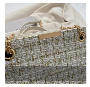 Macro shot of tweed weave texture and golden metal hardware on a crossbody chain bag