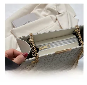 Close-up of smooth gold zipper on white tweed shoulder bag with elegant metal chain