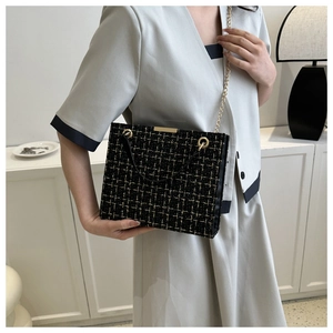 Detail of black and gold tweed shoulder bag with elegant gold chain and leather handle