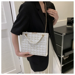 Detail of white tweed shoulder bag with gold chain strap and elegant metallic hardware