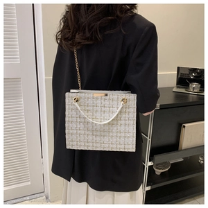 Close-up of elegant tweed shoulder bag featuring gold chain and textured weave material