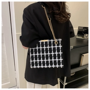 Detail of black and white tweed shoulder bag with gold chain strap on model
