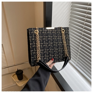 Detail of black gold tweed shoulder bag with elegant chain strap and metal frame
