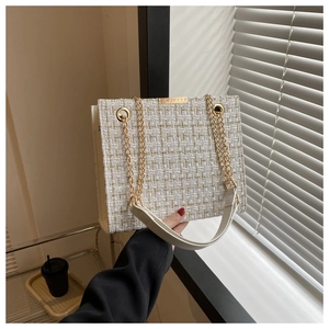 Close-up of beige tweed shoulder bag with gold chain straps and weave texture