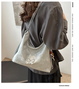 Detail of silver metallic hobo bag featuring a 3D bow buckle and beaded side pendant