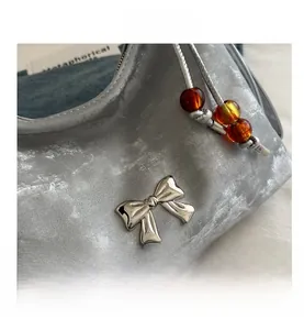 Detail of silver metallic textured bag with a metal bow and amber bead accents
