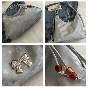 Detail of silver metallic shoulder bag with metal bow and amber bead drawstring