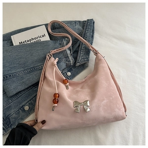 Detail of pink suede bag with silver bow ornament and orange bead pendant charm