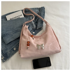 Detail of pink suede crescent bag with silver metal bow and beaded string charm