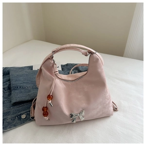 Pink nylon shoulder bag detail featuring a silver metal bow and wooden beaded tassel