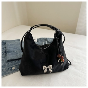 Detail of black satin shoulder bag featuring silver bow and beaded tassel charm decor