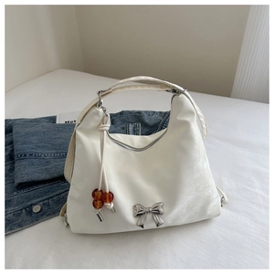 Detail of white half-moon shoulder bag with silver bow and amber bead drawstring