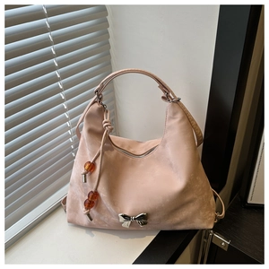 Pink suede handbag detail featuring silver bow hardware and orange beaded charm