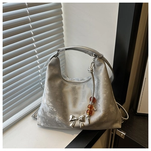 Detail of silver metallic tote with 3D bow buckle and amber bead charm decoration
