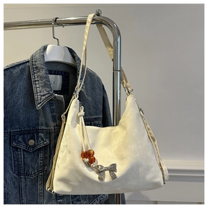 Detail of off-white velvet tote bag with silver bow buckle and amber bead charm