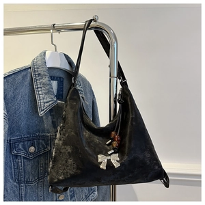 Detail of black hobo bag with silver bow buckle and amber bead charm on denim