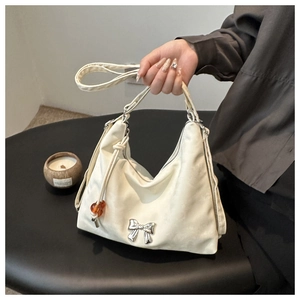 Detail of off-white crescent underarm bag featuring silver bow hardware and drawstring
