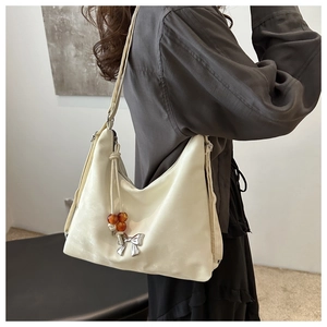 Detail of cream hobo bag with amber beads and silver bow charm shown on shoulder