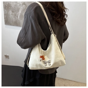 Close-up of white satin shoulder bag featuring silver bow and amber bead drawstring