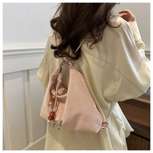 Pale pink triangular backpack featuring silver bow charm and amber bead pendant detail