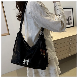 Detail of black velvet hobo bag with silver bow buckle and beaded charm accessory