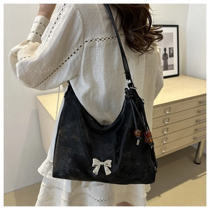 Detail of black suede Hobo bag with silver bow ornament and brown bead pendant