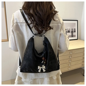 Detail of black tote bag with silver bow charm and colorful beads on textured fabric