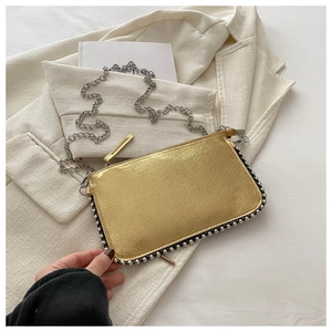 Detail of gold metallic clutch bag with silver beaded edges and fine chain strap