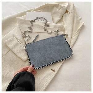 Detail of grey-blue suede handbag with silver bead trim and metal chain strap