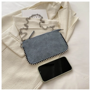 Detailed comparison of blue suede small crossbody bag size next to a smartphone
