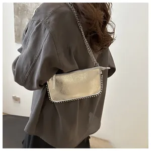 Silver metallic crossbody bag with studded details and chain strap shown on model