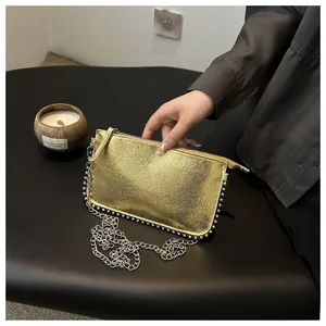 Detail of golden metallic clutch with silver rivet trim and fine chain strap