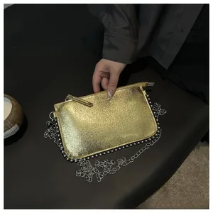 Macro detail of gold textured mini bag with silver chain strap and bead accents