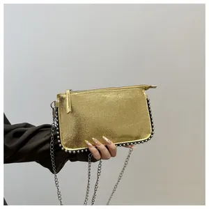 Close-up of golden shoulder bag with metallic rivets and silver chain strap detail