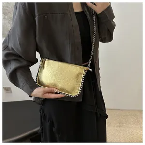 Detail of golden crossbody bag with silver bead studs and delicate metal chain strap