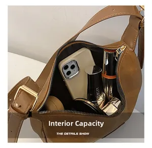 Internal capacity of brown crescent shoulder bag showing phone and cosmetics storage