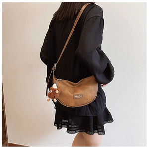 Brown leather crescent crossbody bag with fashion patch and cute plush doll pendant