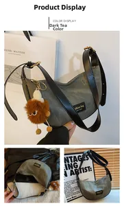 Detail of dark tea crescent bag with denim texture, black strap and plush monster charm