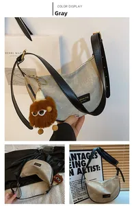 Detail of grey canvas dumpling bag with leather strap and funny plush eye charm