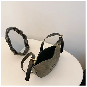 Detail of olive green dumpling bag with textured fabric, leather strap, and gold hardware