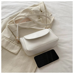 White minimalist crossbody bag on a blazer with gold metal buckles and small square design