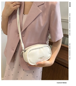 Detail of white leather crossbody bag with gold logo and white chain strap accent