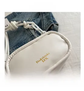Detail view of a white PU leather crossbody bag featuring a chunky chain and golden logo