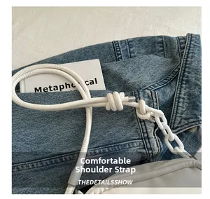 Detail of white leather bag with knot strap and thick plastic chain on denim