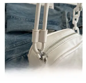 Close-up of white crossbody bag with synthetic leather texture and chunky chain detail