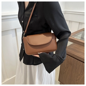 Close-up of brown PU leather crossbody bag with curved flap and gold-tone hardware detail