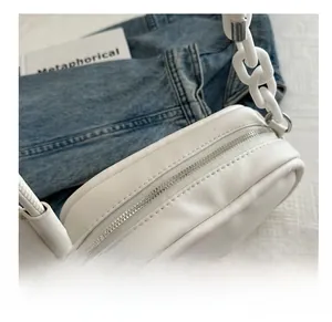 Detail of white PU leather crossbody bag featuring silver zipper and thick chain strap